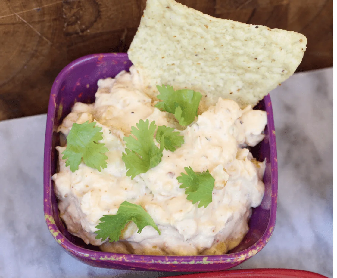 Crockpot Mexican Street Corn Dip in a purple bowl with chip