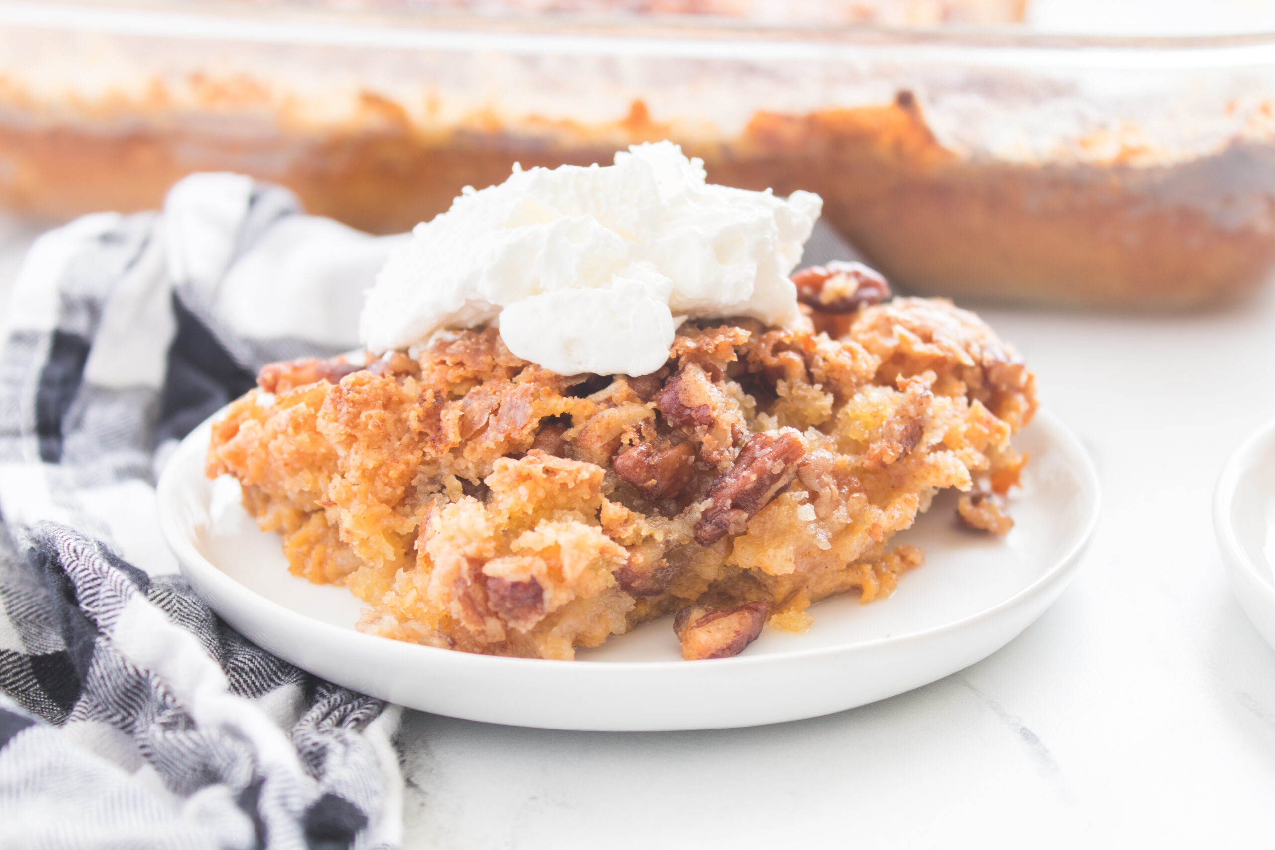 piece of pumpkin spice crunch cake on a plate with whipped cream