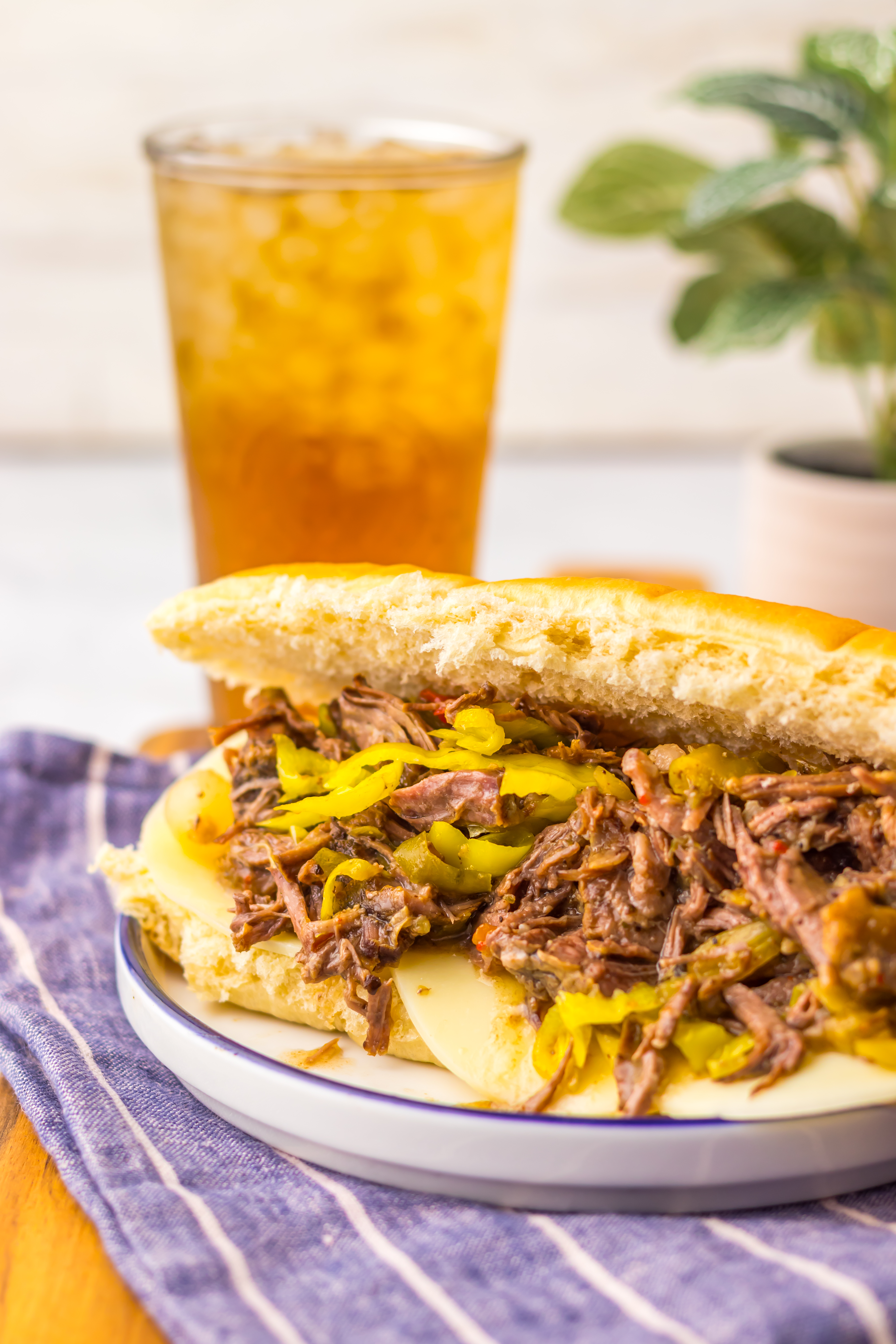 italian beef sandwich on a plate with a glass of tea